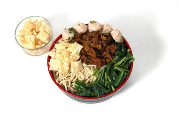A bowl of Mie Ayam, a typical Indonesian dish, featuring chicken noodles with shredded chicken, meatballs, dumplings, green vegetables, and a variety of toppings, isolated on a white background