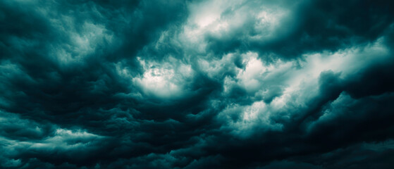 Obraz premium a dramatic and ominous sky filled with dark, swirling storm clouds. The clouds have a turbulent, textured appearance with varying shades of deep teal and gray. Generative AI