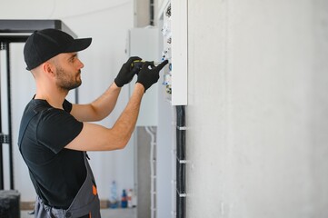 Male electrician working in a switchboard with fuses