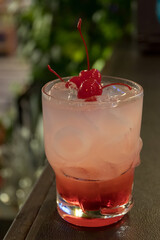 Refreshing cocktail with ice and a cherry, perfect for summer gatherings or relaxing evenings.