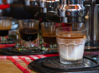 A freshly brewed coffee with layers of espresso and milk, served in a glass. Perfect for coffee enthusiasts and baristas.
