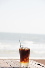 A refreshing glass of iced coffee on a beachside table, perfect for a summer day by the ocean.