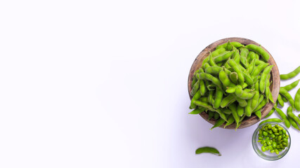 Fresh edamame beans are placed in a rustic wooden bowl, with ample copy space, isolated on a white background