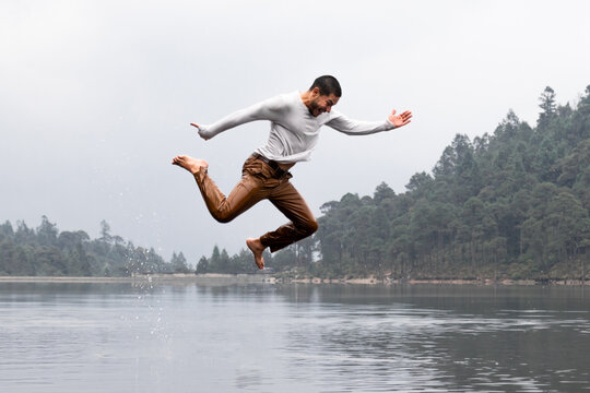 Joy on a rainy day when a man jumps over a misty lake