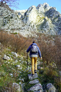 Photographed from behind a tourist with a backpack, climbing a path with a beautiful view. A man is hiking in the mountains above Orahovac - active recreation in the Bay of Kotor, Montenegro.