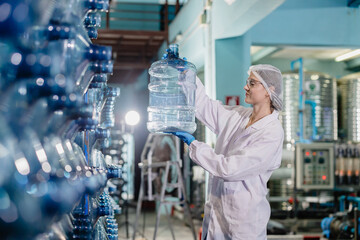 Women worker in drinking water factory working check cleanliness of water bottle gallon storage...