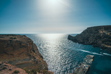 Beautiful sunset landscape in coastal cliff with stone pier in Mellieha, Malta