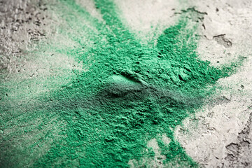 Green spirulina algae powder on dark background - healthy nutritional supplement