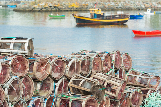 Pile of fishing traps with boats and water in the background