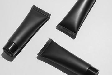 Black cosmetic tubes on minimalist white background