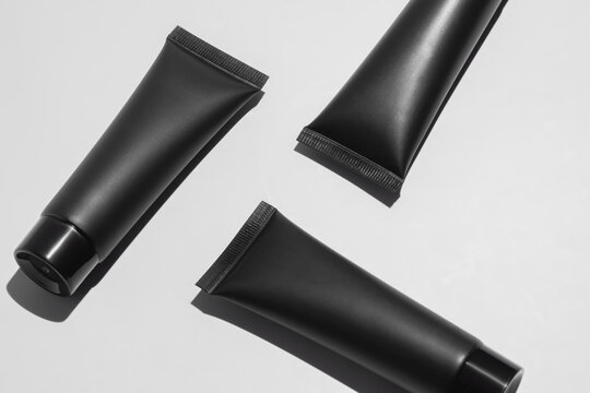 Black cosmetic tubes on minimalist white background