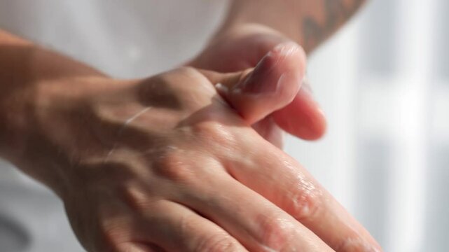 A man moisturizes his hands with thick cream.
Hand care.
Man's hands.
Skin problems.
Dry hands.
Body balm