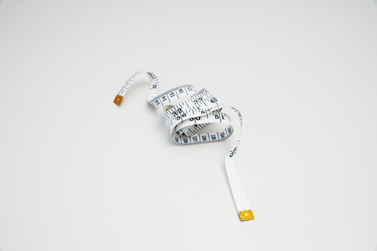 Top view of a simple measurement tape coiled on white background