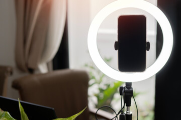 Mobile phone and ring lamp in cozy room at home or office. Equipment for blogging and recording video