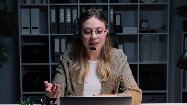 Positive female Caucasian it support worker talking with customer during online consultation in the office. Remote conversation, negotiation concept.