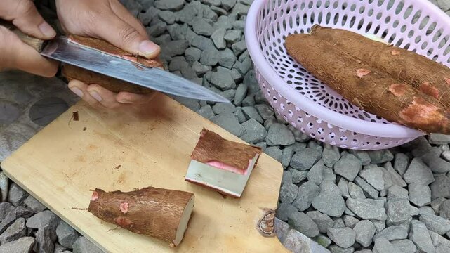 peel skin,and slice raw cassava (tapioca) root using knife in a wood cutting board, cooking, preparation,4K.