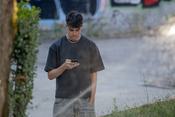 young man or teenager with mobile phone in summer on the street