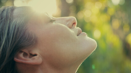 Young woman with closed eyes against the sun