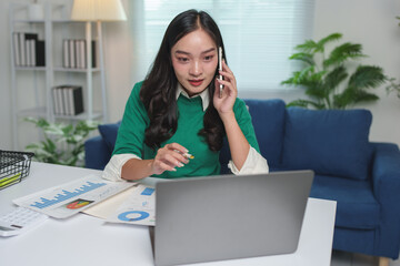 Young businesswoman talking on the phone at work Contacting customers in a modern office.To conduct business on a mobile phone at work using a laptop computer startup business idea.