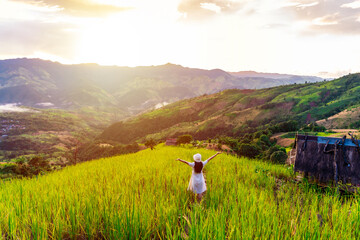 Fototapeta premium Happy young woman traveler relaxing and looking at the beautiful sunrise on the top of mountains, Travel lifestyle concept