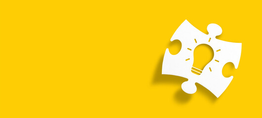 Creative idea, inspiration, new idea and innovation concept. White puzzle piece with light bulb shape on yellow background.