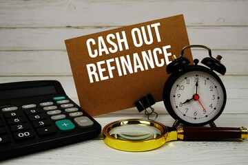 Cash Out Refinance text on paper card with alarm clock, calculator and magnifying glass on wooden background