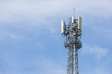 A cellphone tower stands tall against the sky, its structure silhouetted by the vast blue backdrop. The image captures the intersection of technology and the natural world.