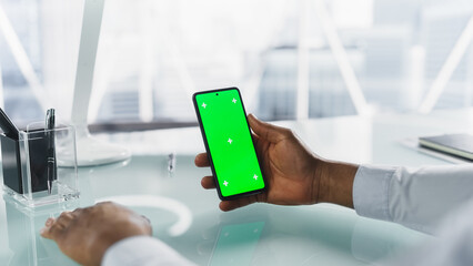 Anonymous Person Using a Smartphone with Mock Up Green Screen Chromakey Display with Motion Tracker Placeholders. Office Manager Browsing Internet, Online Shopping, Swiping and Tapping on the Phone