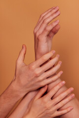 Close-up of well-groomed natural female and male hands. Beige background. A neat manicure. A young man and a woman holding arms.