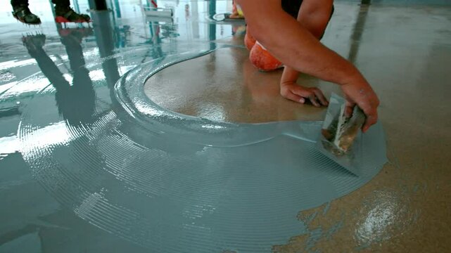 Epoxy floor Construction worker spreading self leveling concrete on the floor in slow motion