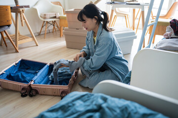 Obraz premium Asian girl preparing vacation in bedroom. Woman doing checklist before holidays trip in university dormitory or preparing to move out.