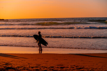 A man is walking on the beach with a surfboard