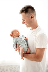 dad with a newborn baby son, dad holding the baby in his arms gently hugging and kissing him,...