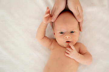 mom's hands hold the baby, a newborn baby with open eyes on a white isolated background, a place...