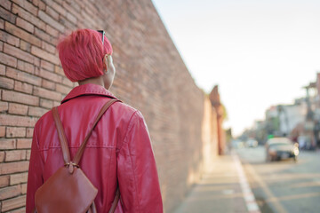 Gen z girl leather fashion with punk Asian woman tourist of local city Southeast Asia travel trendy pink hairstyle young female punk traveler walking around in town