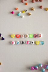 Friends forever written with colorful beads. Jewelry making supplies on the table. Making friendship bracelets concept. Flat lay.