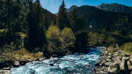 Cat Bridge. Old historical stone bridge located on the stream in Rize Camlihemsin. Photo of the man with the yellow hoodie standing on the bridge.