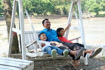 Happy father and sons relaxing on swing together