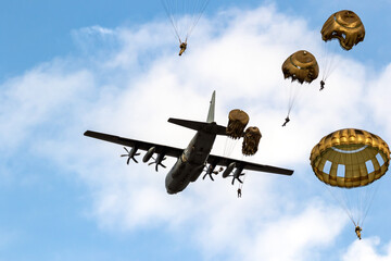 Military parachutist paratroopers parachute jumping out of a transport plane. 