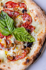 Pizza tradizionale napoletana con salame piccante, funghi, mozzarella e basilico fresco servita in una pizzeria elegante