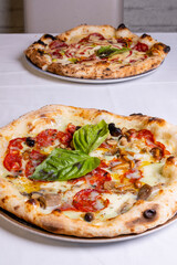 Pizza tradizionale napoletana con salame piccante, funghi, mozzarella e basilico fresco servita in una pizzeria elegante