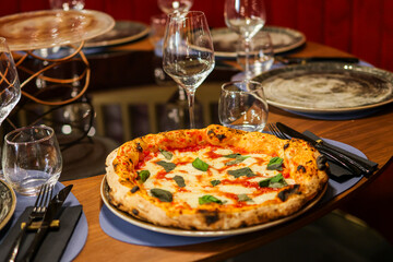 Pizza margherita tradizionale napoletana con sugo di pomodoro, mozzarella e basilico fresco servita in una pizzeria elegante