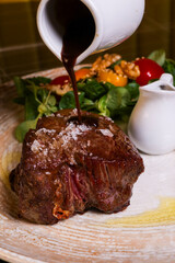 Filetto di manzo con cottura al sangue servito in un ristorante elegante con la riduzione della sua salsa, insalata verde e insalata di cavolo come contorno