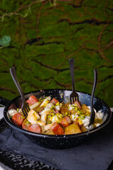 Porzione di patate al forno con mozzarella filante, mortadella e granella di pistacchio servita come antipasto in un pub con delle forchettine di plastica