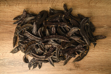 Carob fruits and carob seeds on wooden background