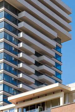 A high-rise building characterized by its multiple balconies, creating a geometric pattern against a clear blue sky, demonstrating architectural ingenuity and urban living.