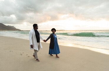 Loving African couple walking hand in hand on a beach at dusk
