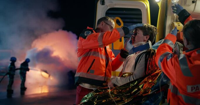Ambulance Medical Staff Performing Safety Checks on a Car Crash Victim. Caucasian Doctor and Female Paramedic Inspecting a Young Patient with the Help of a Flashlight. Shining Light into the Eyes