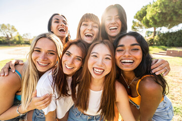 Multiethnic group of young women smiling at camera outside - Happy girls laughing walking at the park - Female community concept with diverse girlfriends having fun outdoors - Bright filter