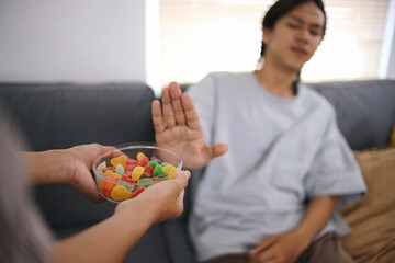 Young Man Rejecting Sugar Candy With Hand Refusing Gesture. No Sugar Concept